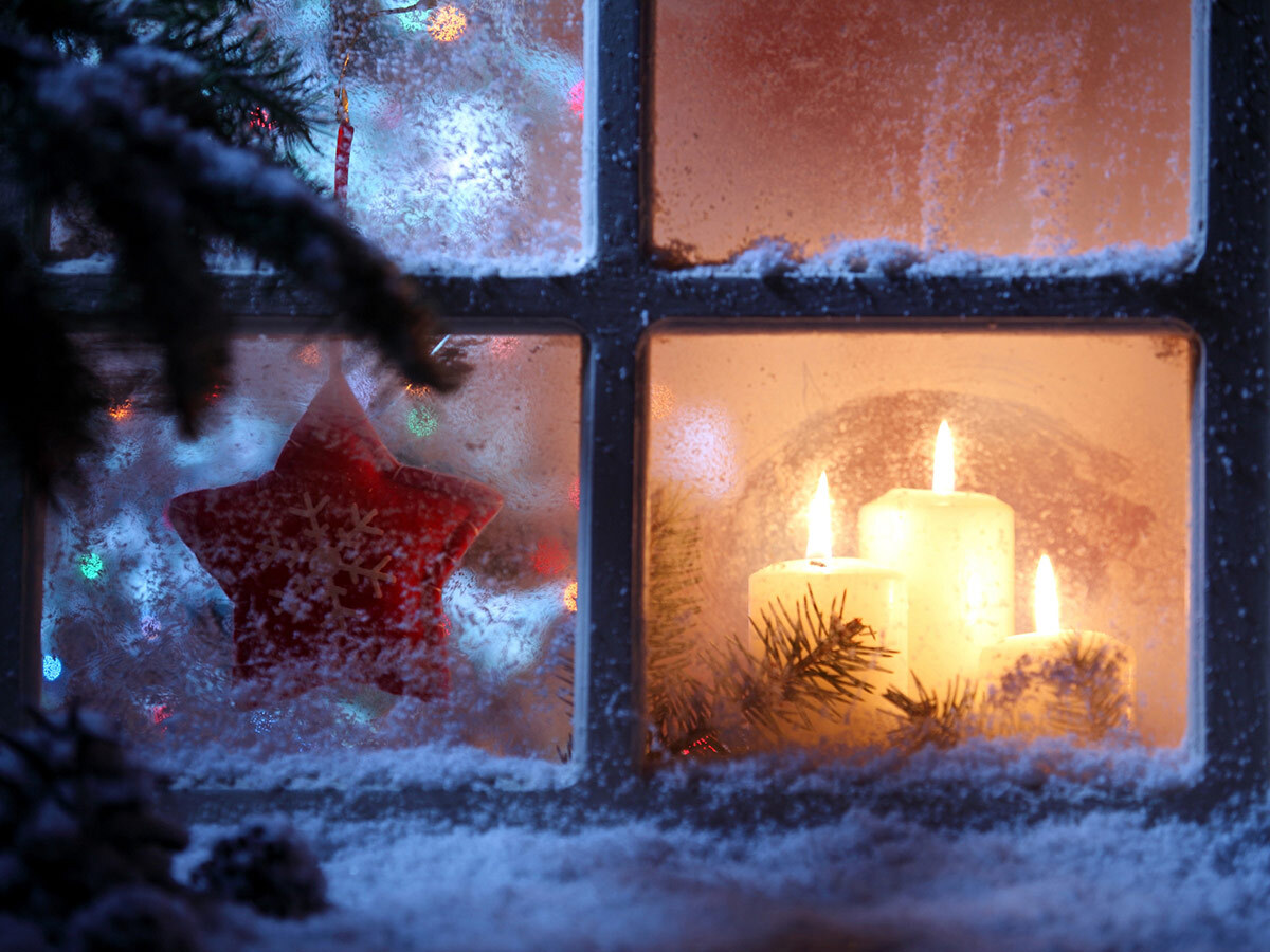 Advent candles and an illuminated star glowing in a dark December window