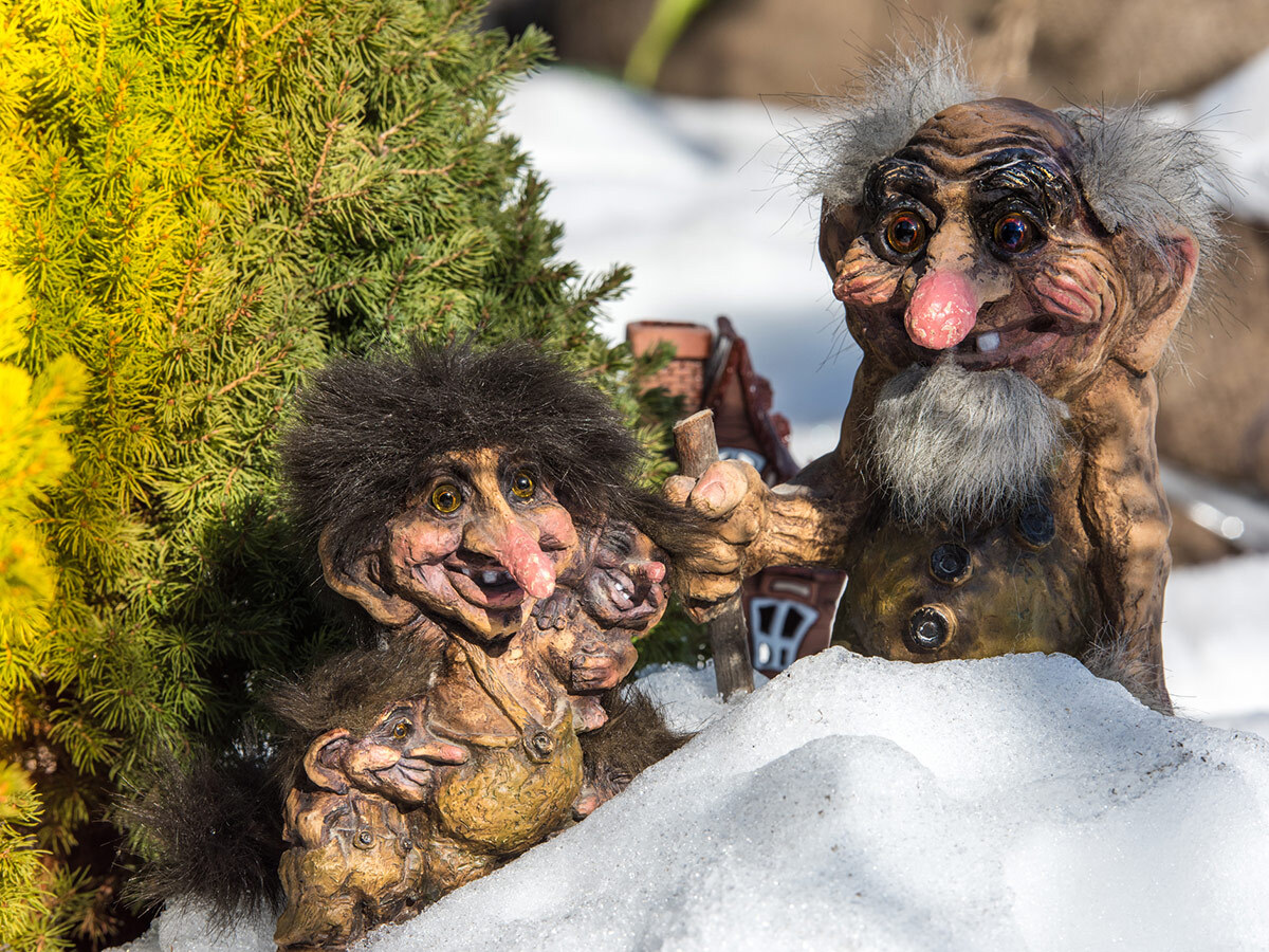Two Norwegian troll figures with wild hair peeking out of the snow