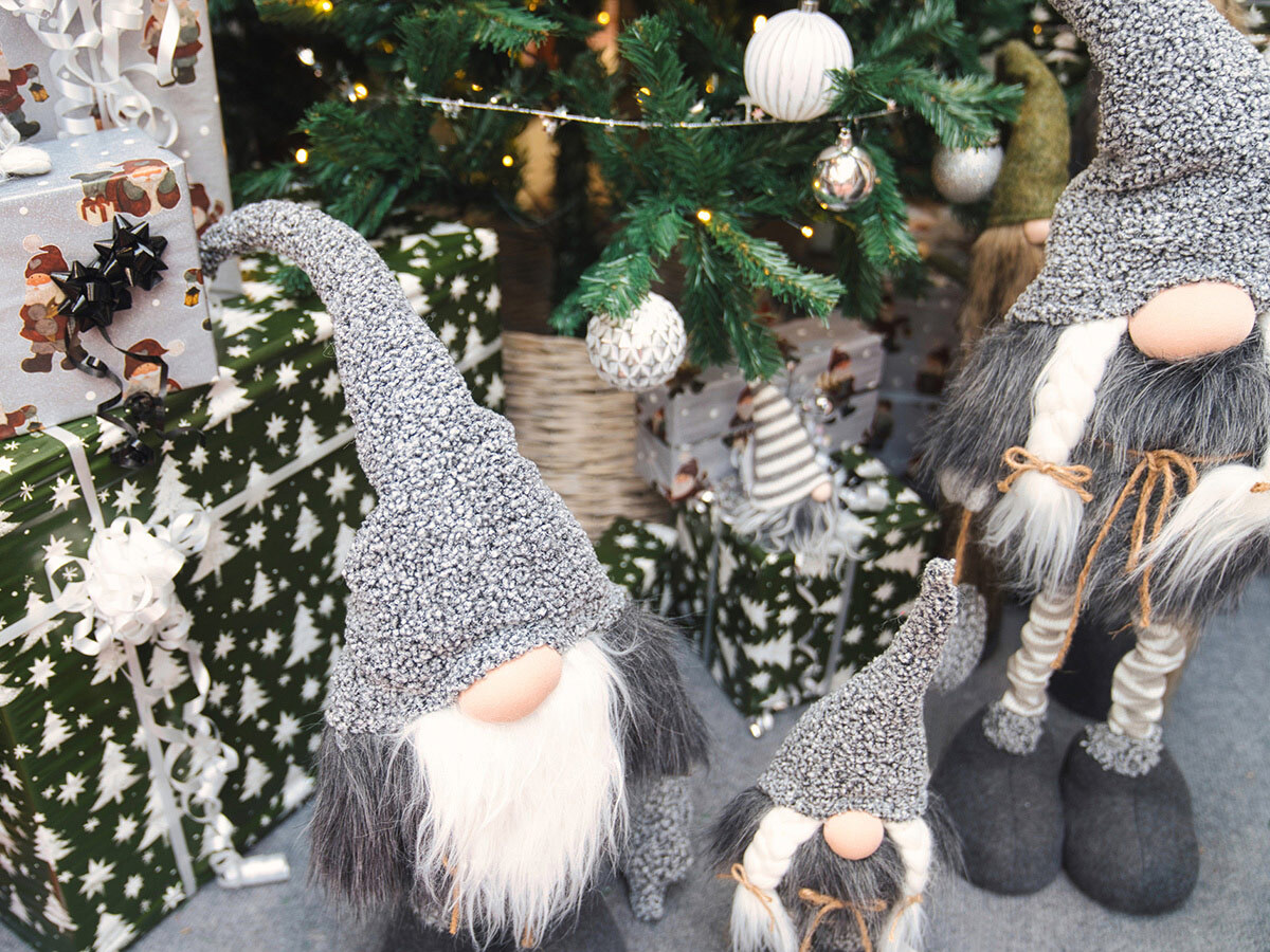 Red-capped tomte figures gathered around a Christmas tree